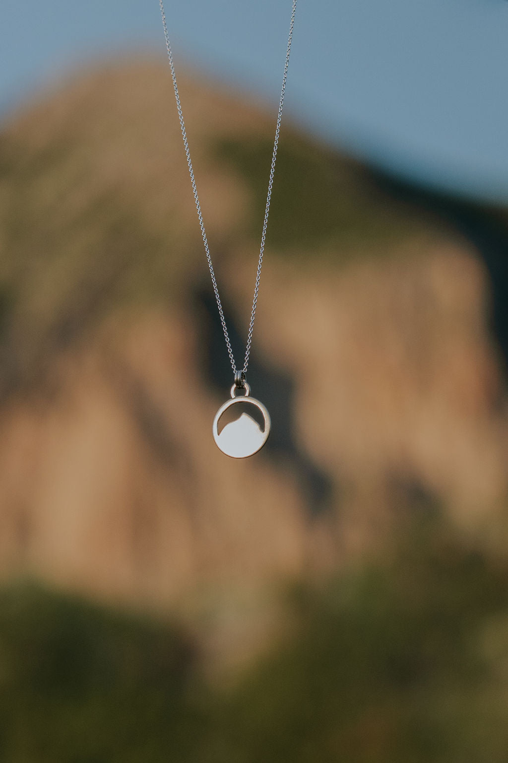 Necklace with Mount Crested Butte pendant against a blurred natural background