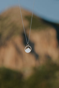 Necklace with Mount Crested Butte pendant against a blurred natural background