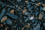Load image into Gallery viewer, Silver Mount Crested Butte necklace with a pendant on pebbles
