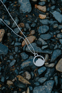 Silver Mount Crested Butte necklace with a pendant on pebbles